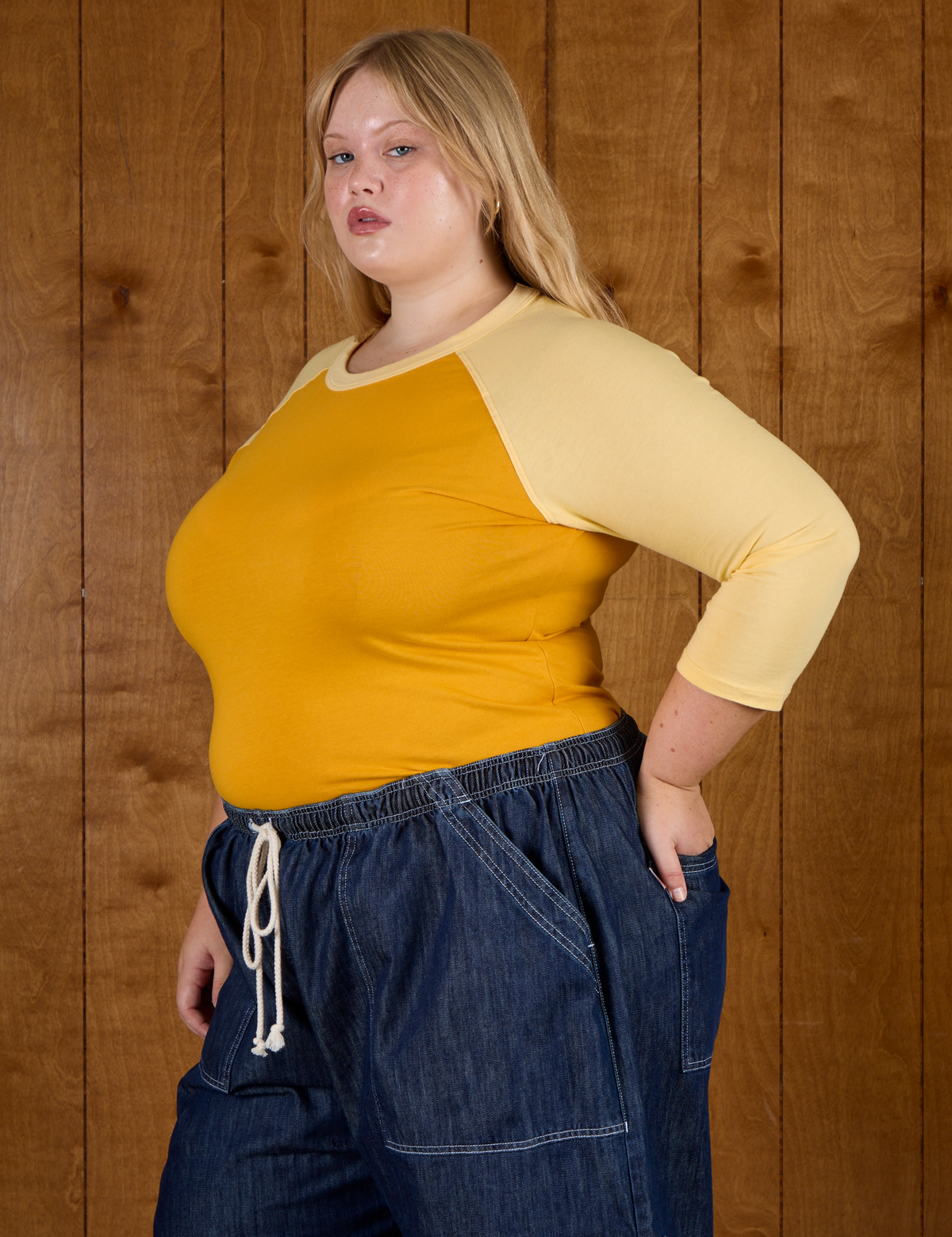 Side angled view of Juliet wearing the Mustard Yellow/Butter Raglan Tee
