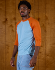 Angled side view of the Baby Blue/Orange Colorblock Raglan Tee on Isaac