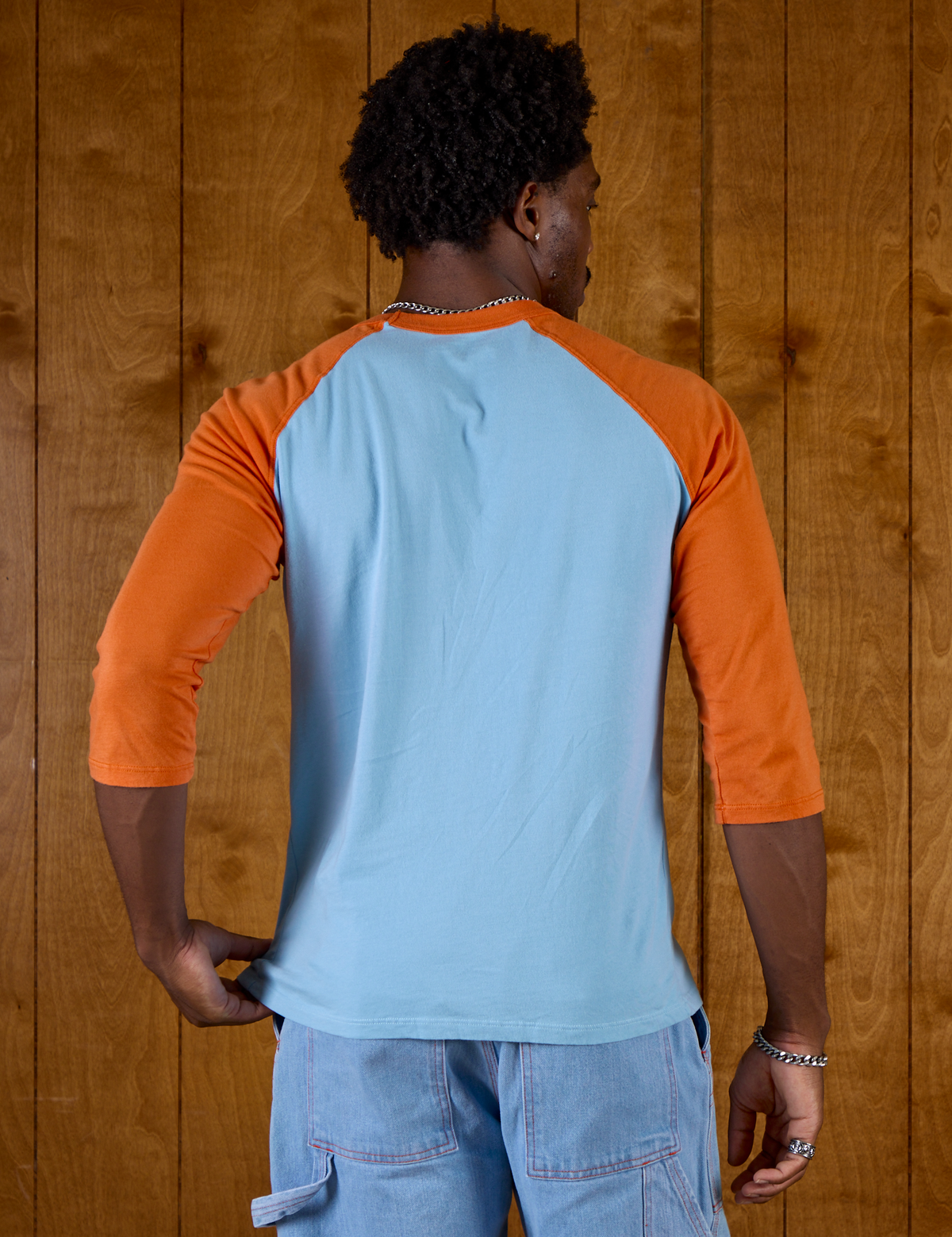 Back view of Isaac wearing the Baby Blue/Orange Colorblock Raglan Tee