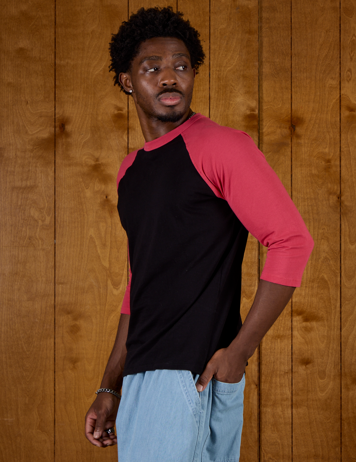 Angled side view of Isaac wearing the Black/Pink Colorblock Raglan Tee