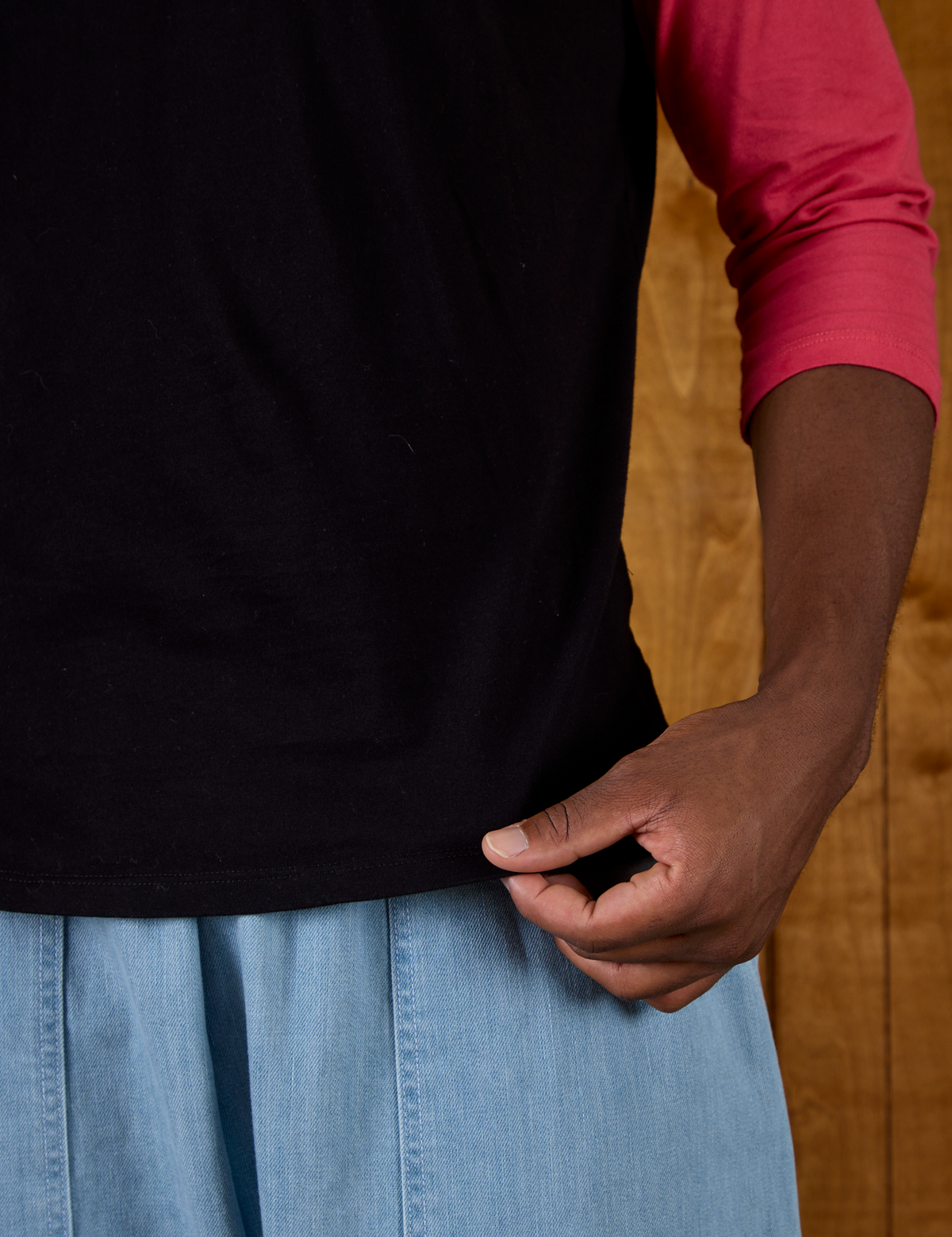 Close up of the hem on the Black/Pink Colorblock Raglan Tee worn by Isaac