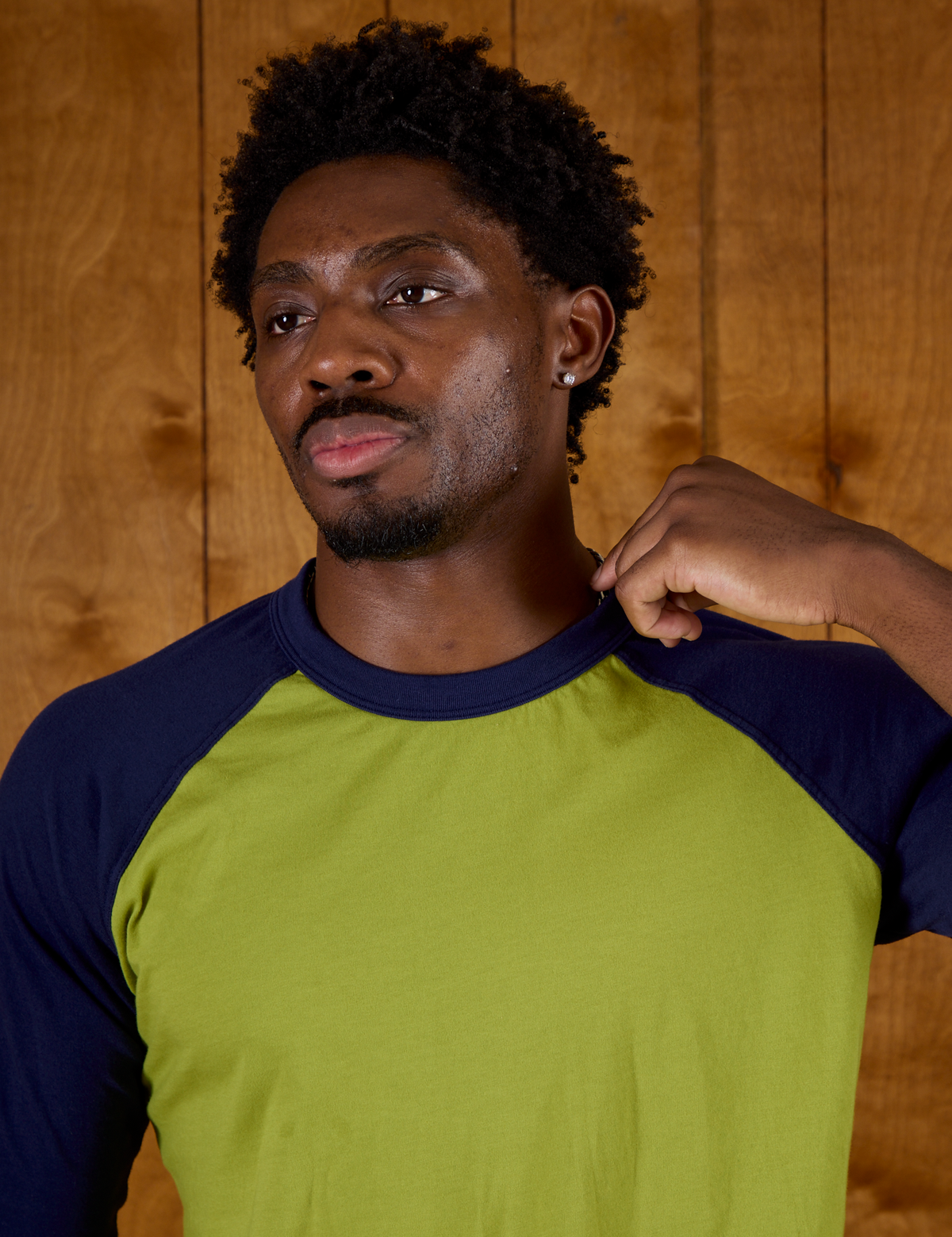 Close up of Isaac wearing  the Gross Green/Navy Colorblock Raglan Tee