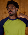 Close up of Isaac wearing  the Gross Green/Navy Colorblock Raglan Tee