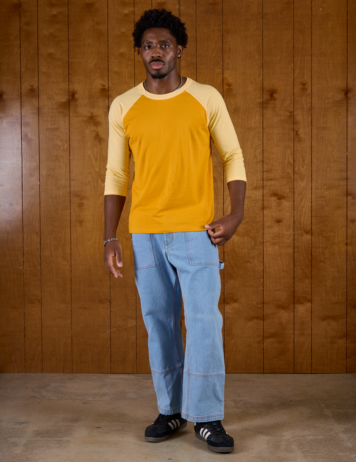 Isaac wearing the Mustard Yellow/Butter Raglan Tee with Light Wash Carpenter Jeans