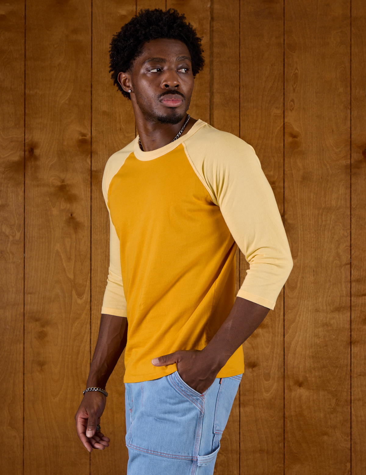 Angled side view of Isaac in the Mustard Yellow/Butter Raglan Tee