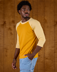 Angled side view of Isaac in the Mustard Yellow/Butter Raglan Tee