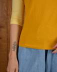 Close up of hemline on the Mustard Yellow/Butter Raglan Tee worn by Alex