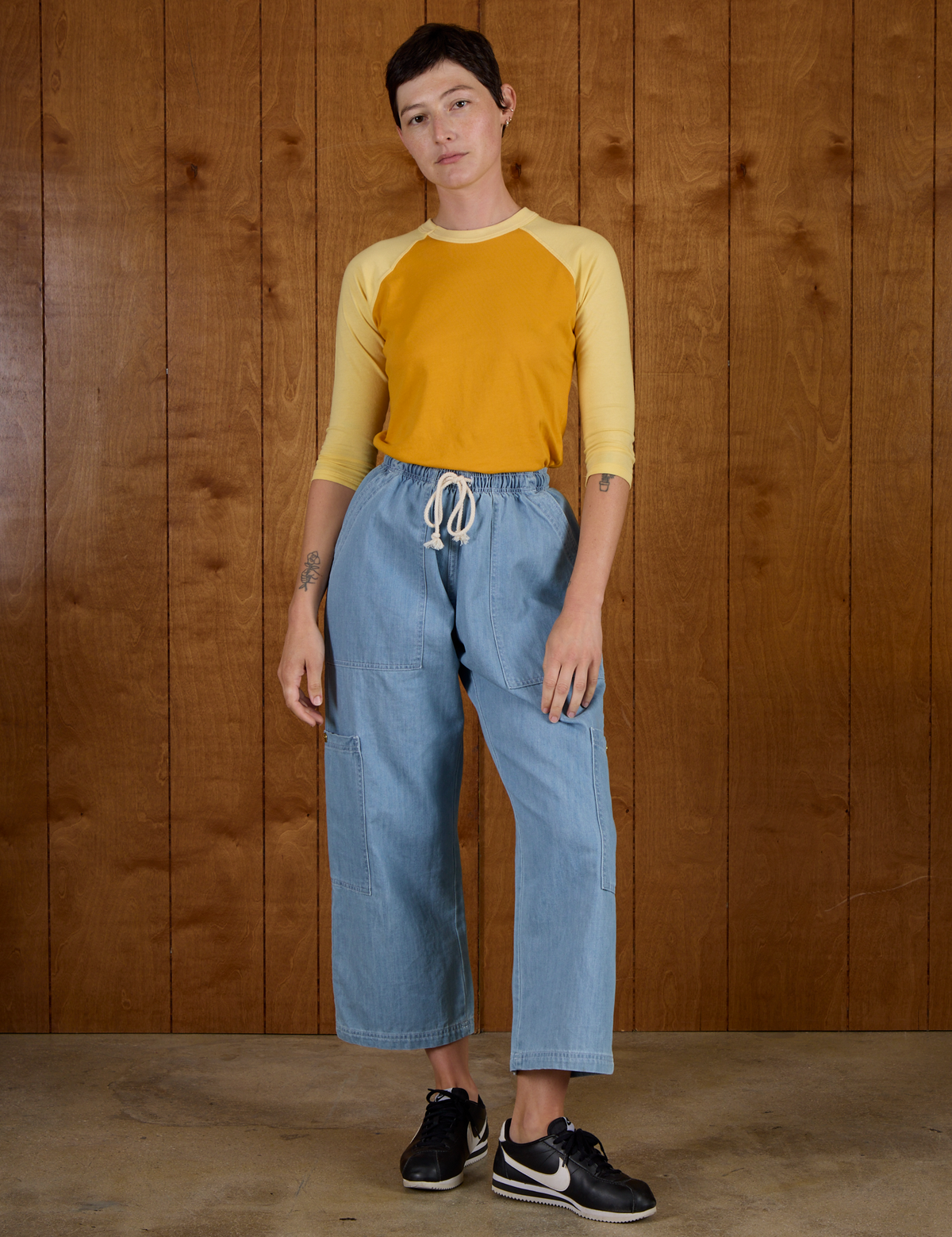 Alex wearing the Mustard Yellow/Butter Raglan Tee tucked into Light Wash Drop Pocket Pants