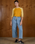 Alex wearing the Mustard Yellow/Butter Raglan Tee tucked into Light Wash Drop Pocket Pants