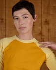 Close up of Alex wearing the Mustard Yellow/Butter Raglan Tee