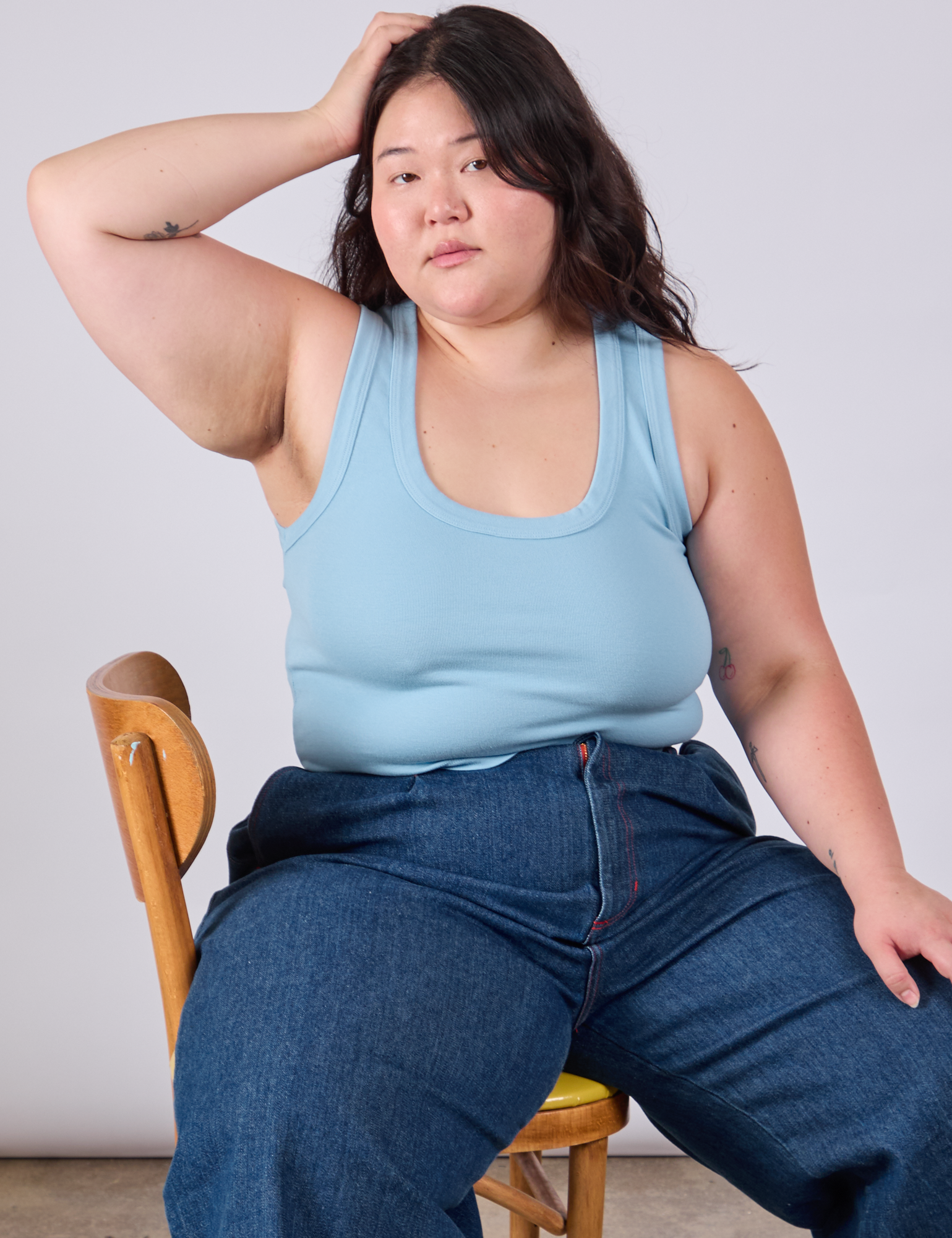 Ashley is sitting in a chair wearing Cropped Tank Top in Baby Blue and dark wash Indigo Wide Leg Trousers