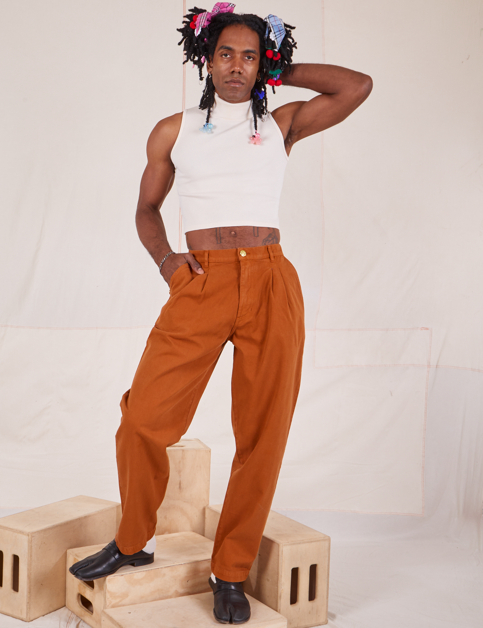 Jerrod is 6&#39;3&quot; and wearing S Long Heavyweight Trousers in Burnt Terracotta paired with vintage off-white Sleeveless Turtleneck