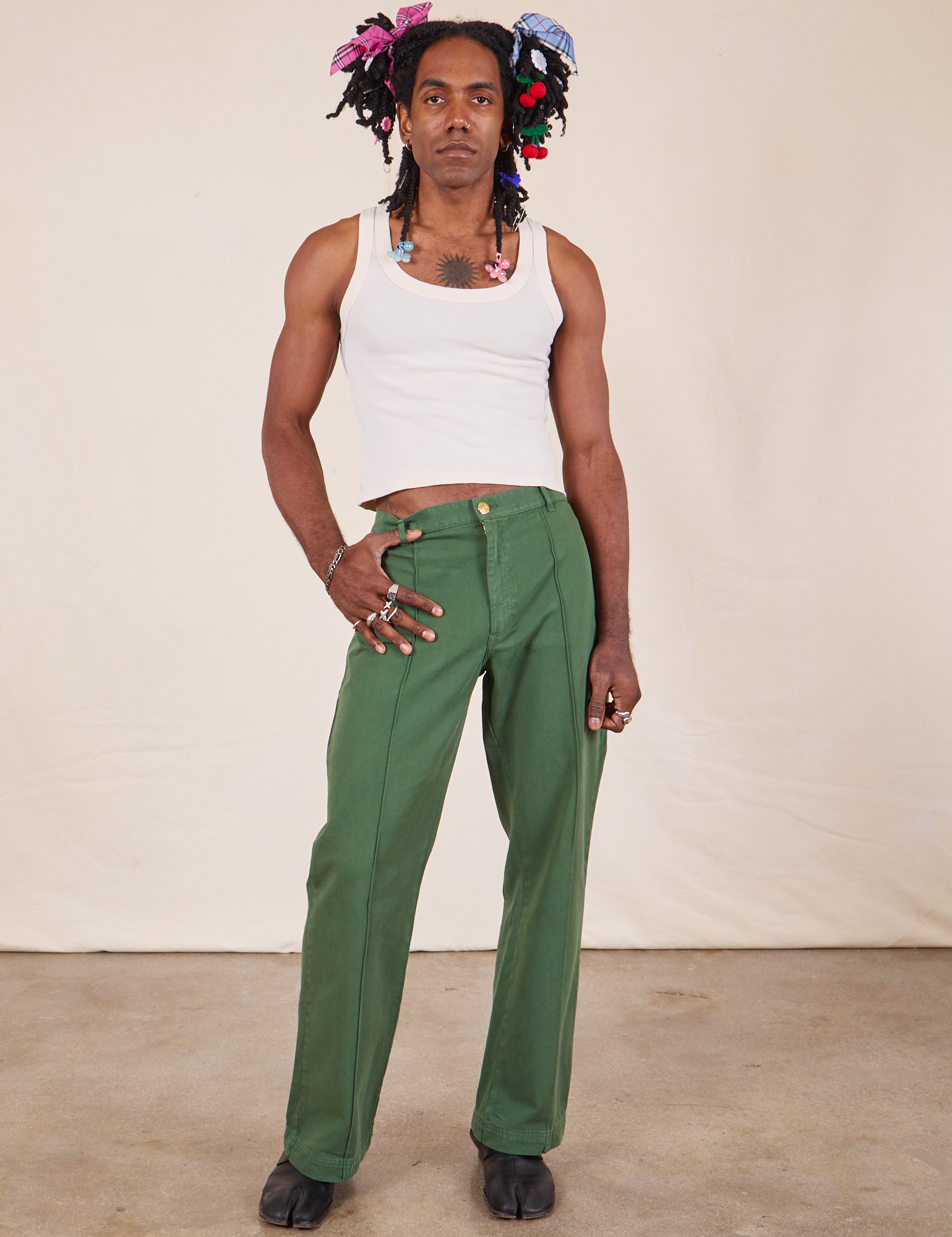 Jerrod is 6&#39;3&quot; and wearing M Long Western Pants in Dark Emerald Green paired with vintage off-white Cropped Tank Top