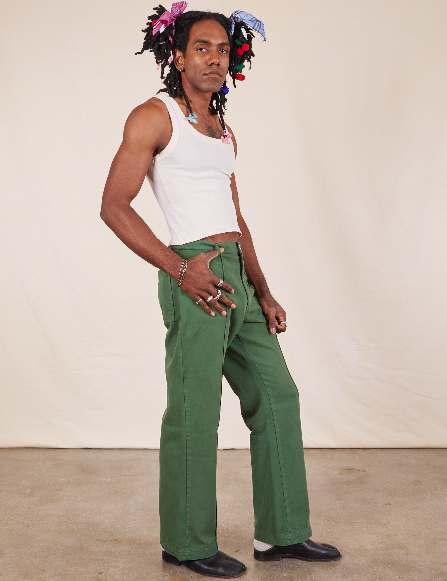 Side view of Western Pants in Dark Emerald Green and vintage off-white Cropped Tank Top on Jerrod