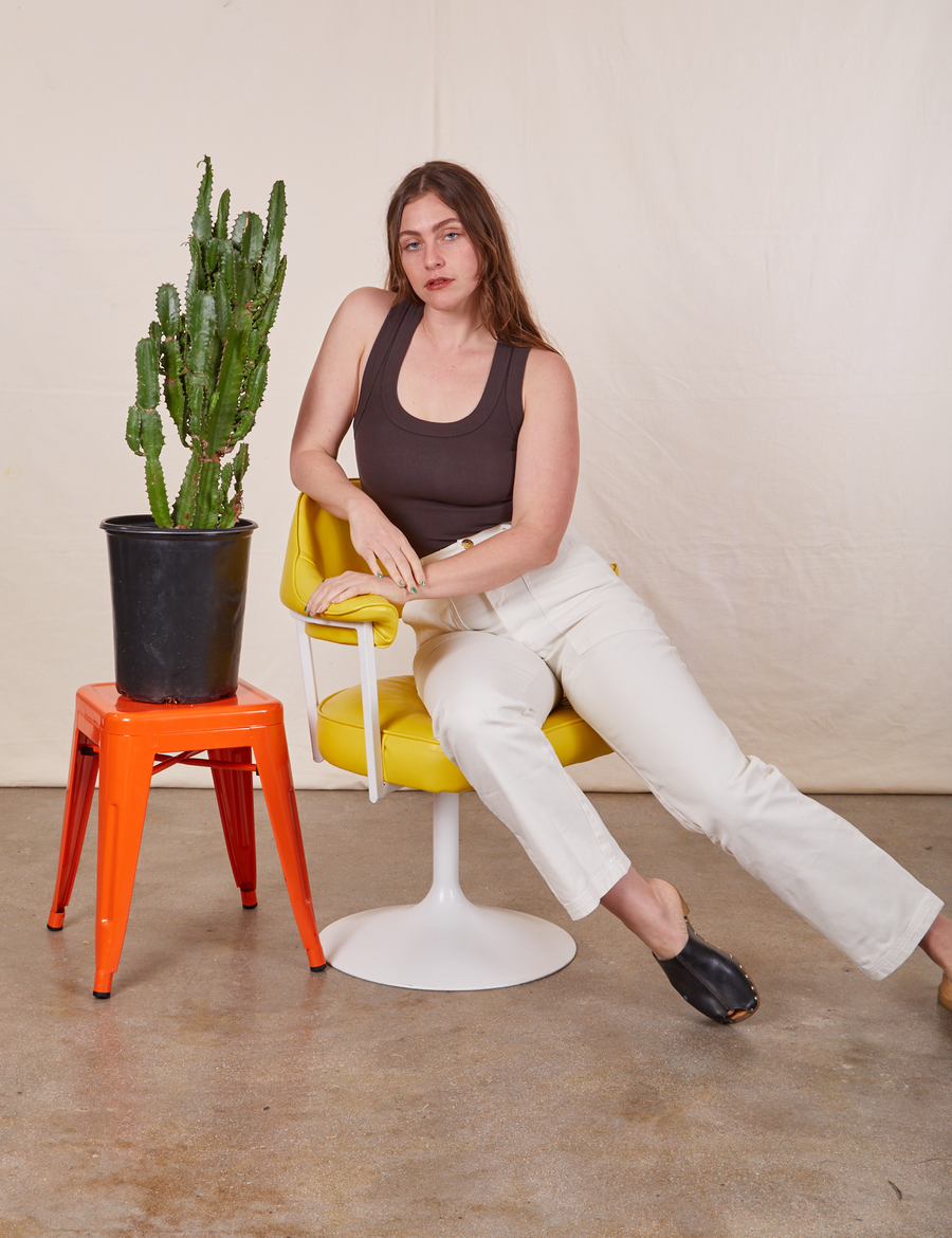 Allison is sitting in a yellow and white chair wearing Work Pants in Vintage Tee Off-White and an espresso brown Tank Top