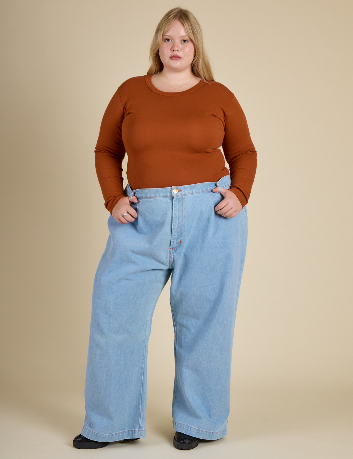 Juliet is wearing the Burnt Terracotta Long Sleeve Baby Tee with Light Wash Wide Leg denim Trousers