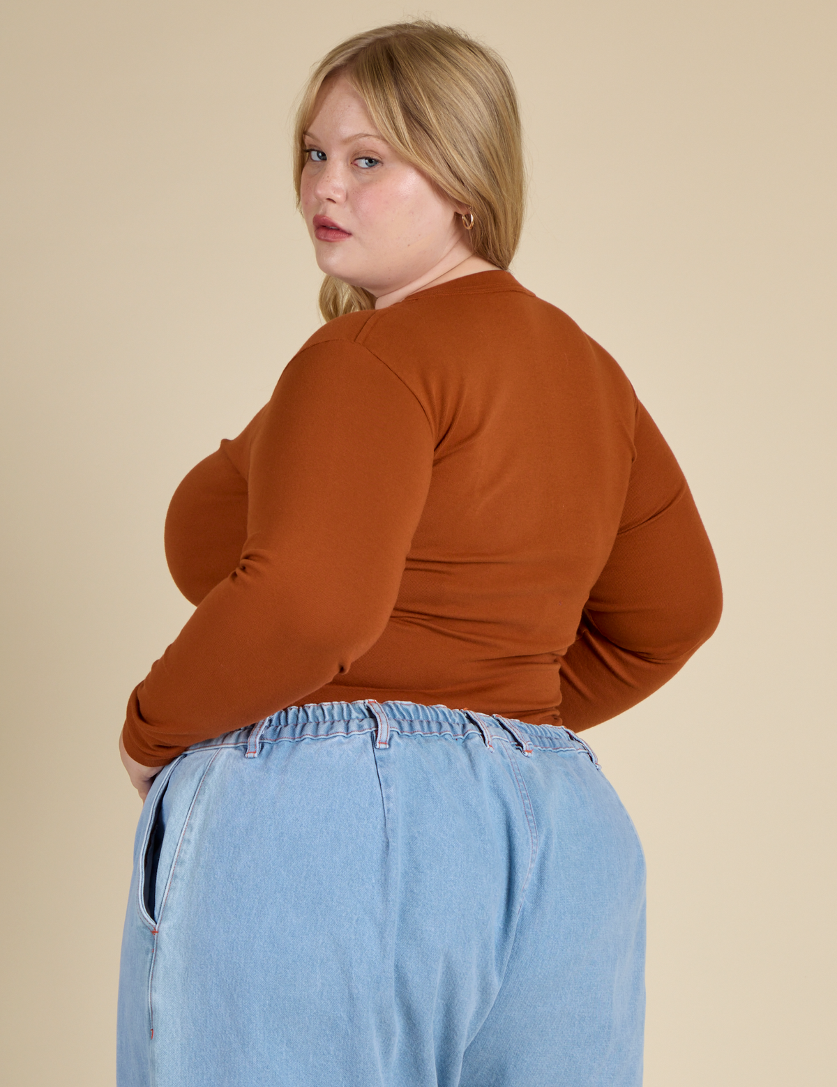 Angled back view of Juliet wearing the Burnt Terracotta Long Sleeve Baby Tee