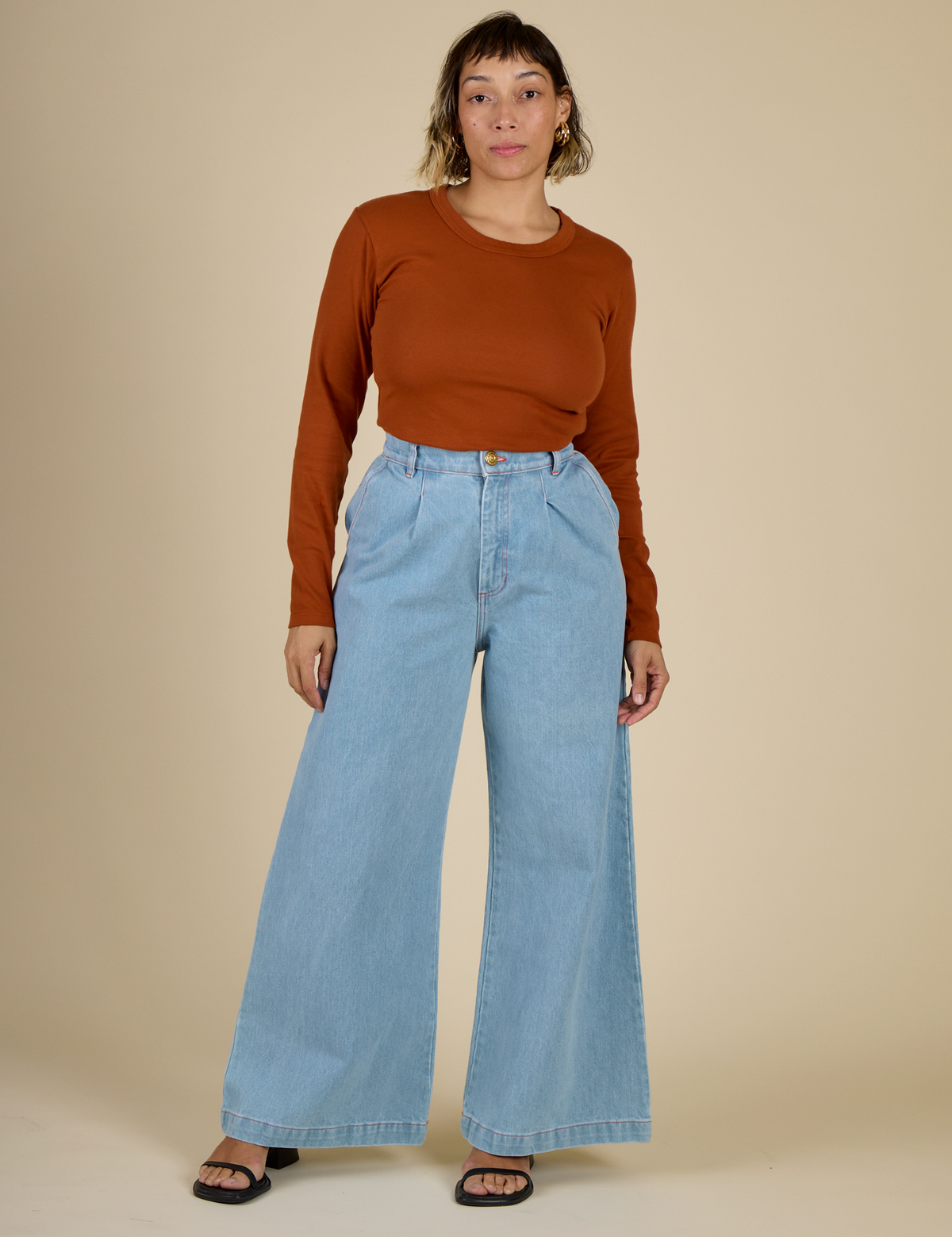 Tiara wearing the Burnt Terracotta Long Sleeve Baby Tee tucked into Light Wash Wide Leg Denim Trousers