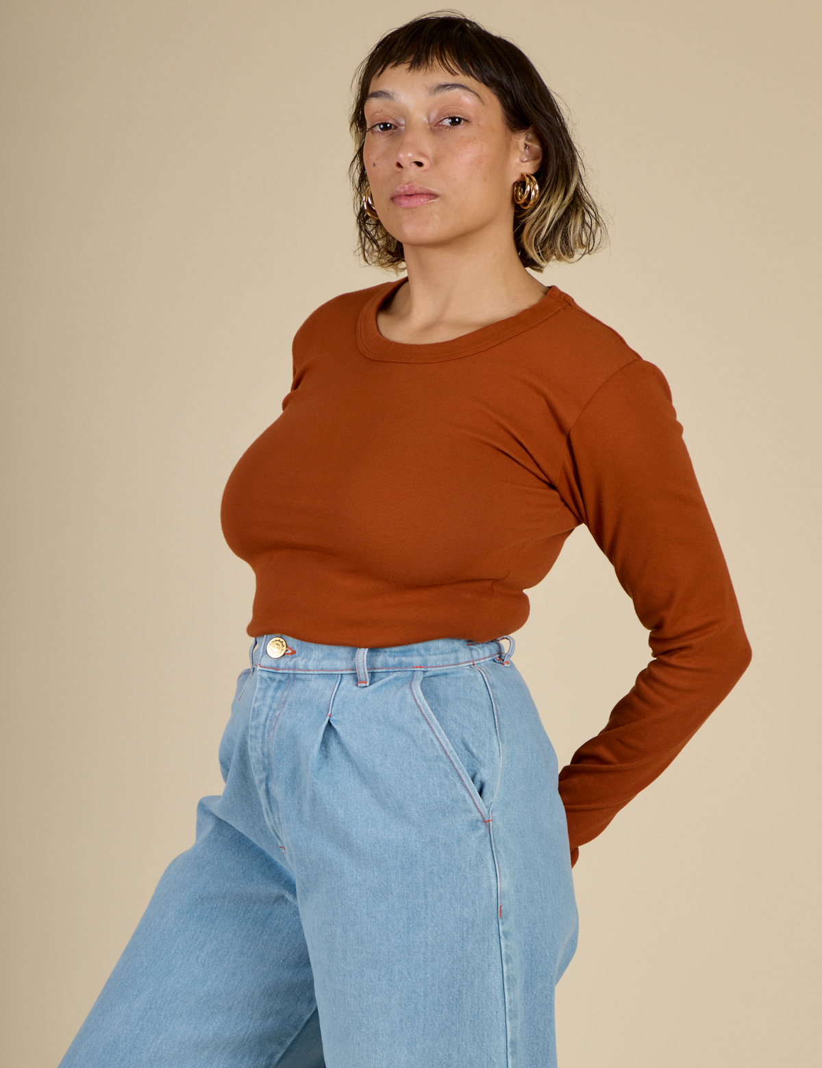 Angled side view of Tiara in the Burnt Terracotta Long Sleeve Baby Tee