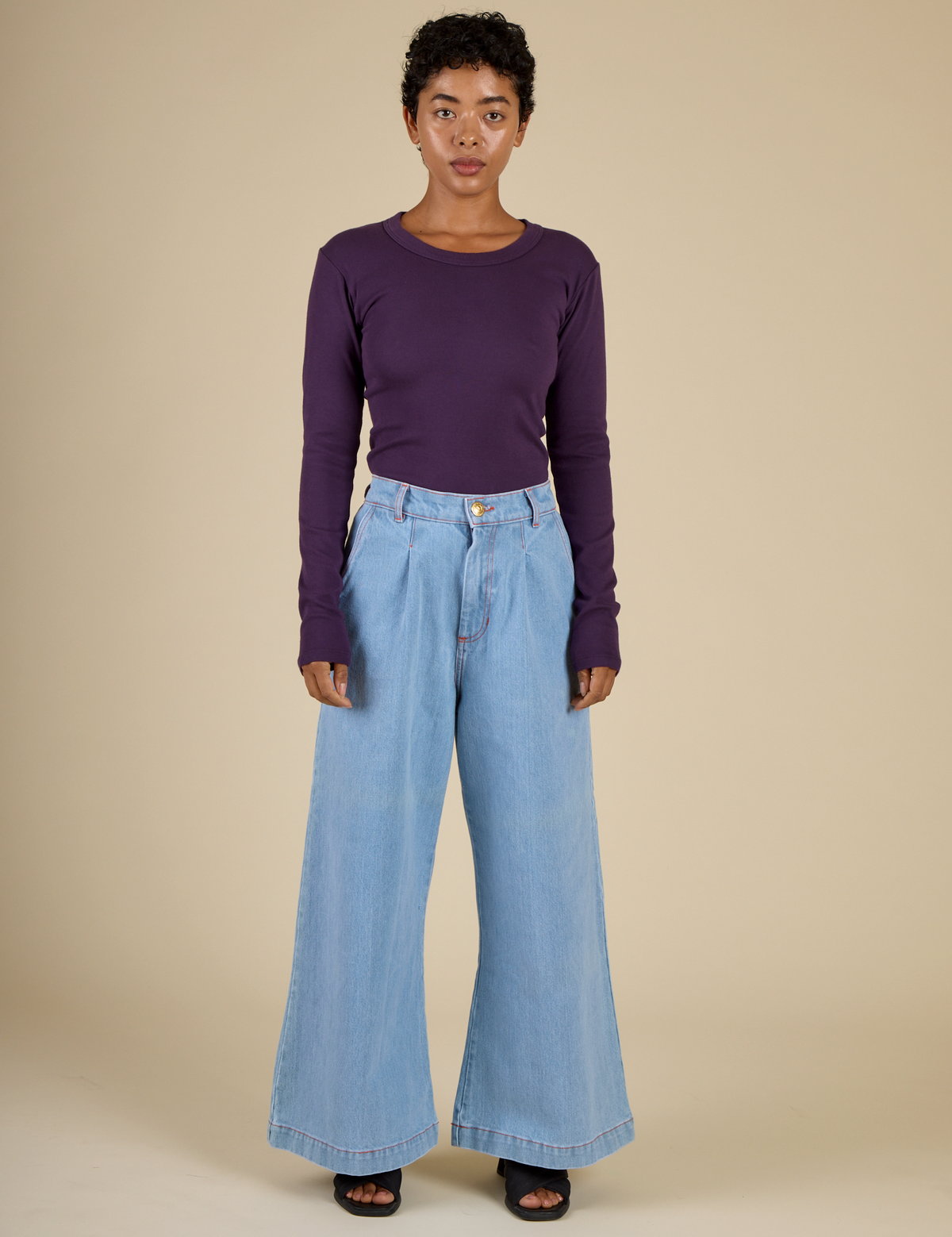 Mika is wearing the Nebula Long Sleeve Baby Tee tucked into the Petite Light Wash Wide Leg Trousers