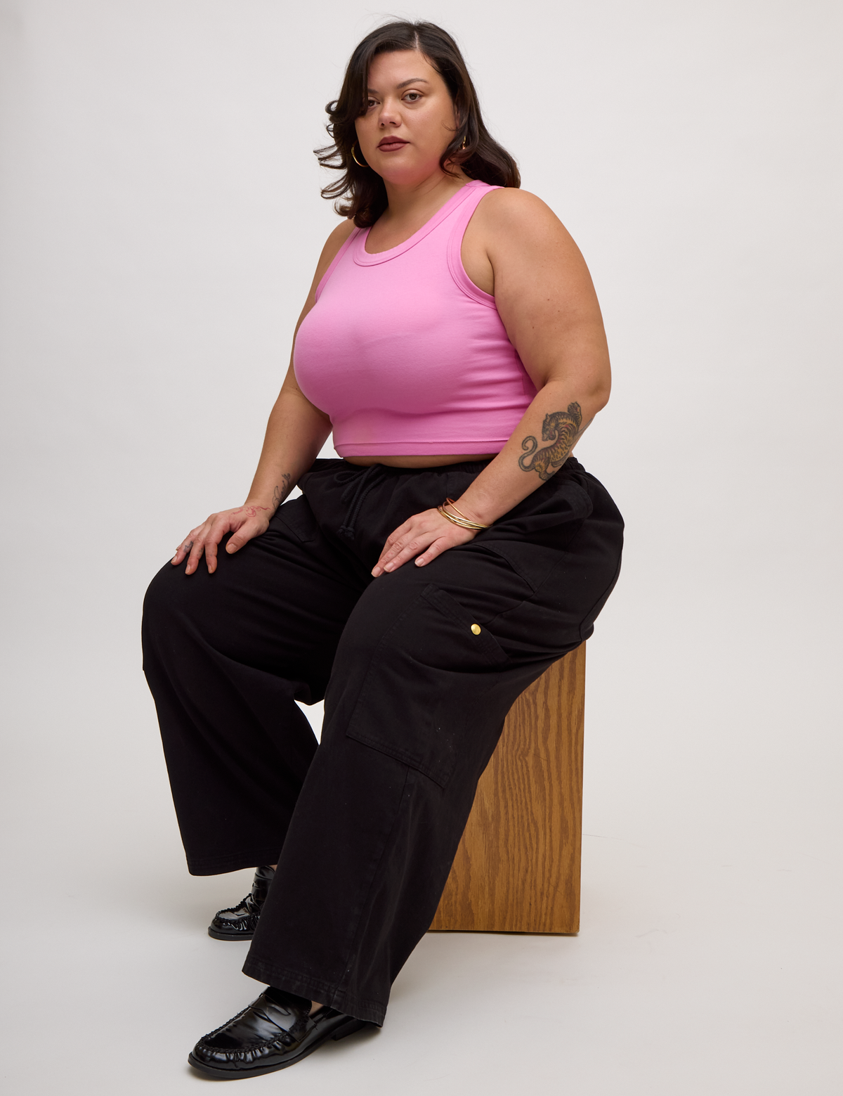 Angled side view of Kristen wearing the P Bubblegum Pink Deep Cut Racerback and Black Drop Pocket Pants