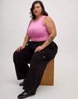 Angled side view of Kristen wearing the P Bubblegum Pink Deep Cut Racerback and Black Drop Pocket Pants