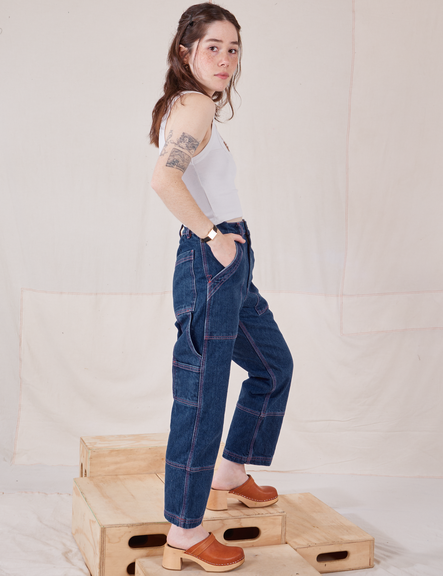 Side view of Petite Carpenter Jeans in Dark Wash and vintage off-white Cropped Tank on Hana