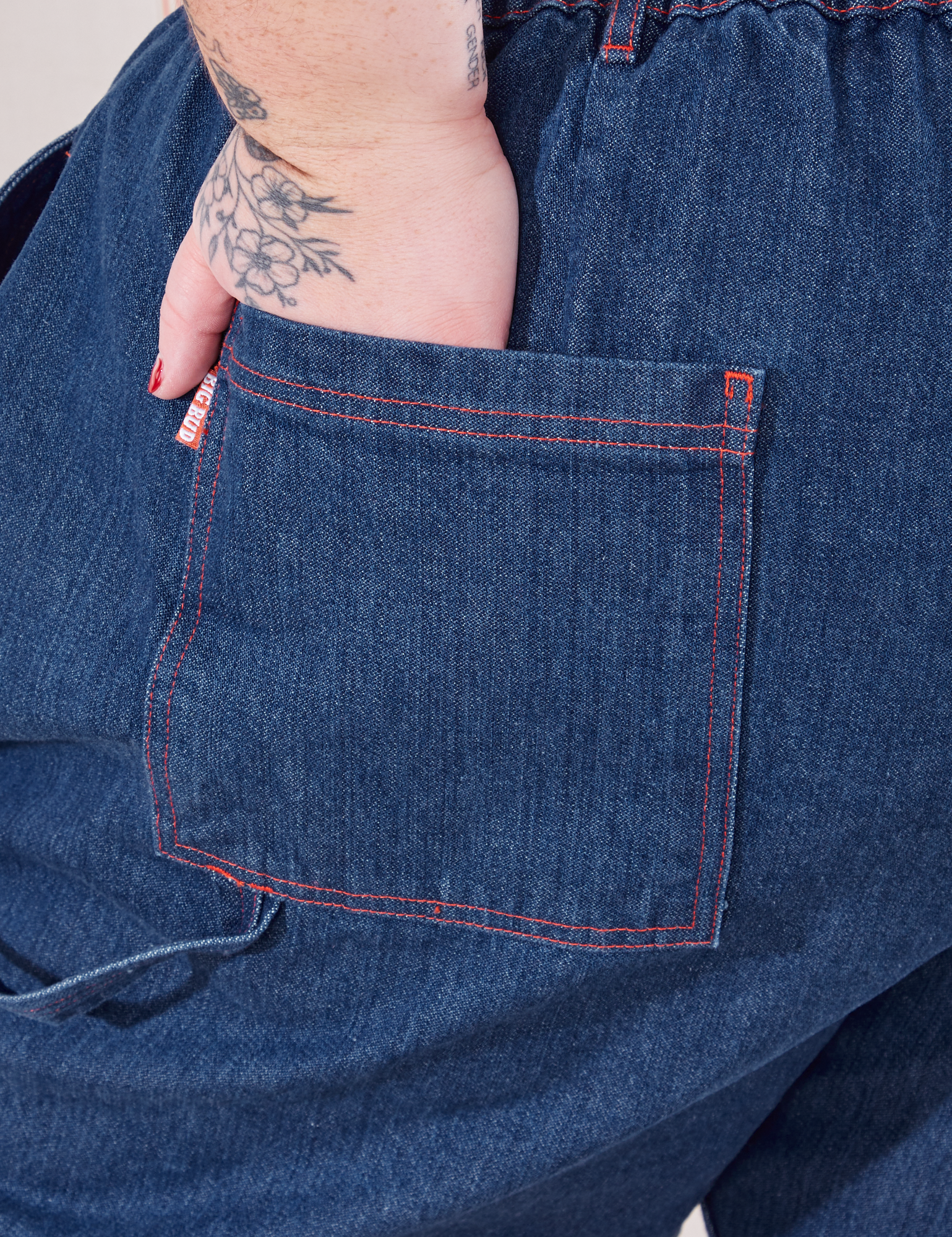 Petite Carpenter Jeans in Dark Wash back pocket close up. Jordan has their hand in the pocket.