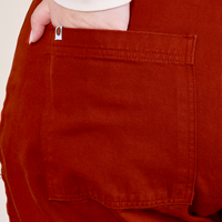 Back pocket close up of Western Pants in Paprika. Worn by Ashley with her hand in the pocket.