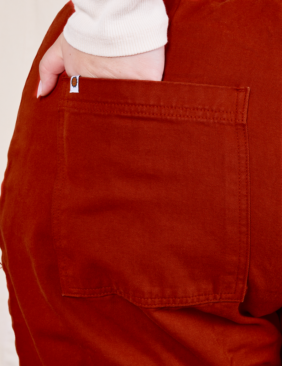 Back pocket close up of Western Pants in Paprika. Worn by Ashley with her hand in the pocket.