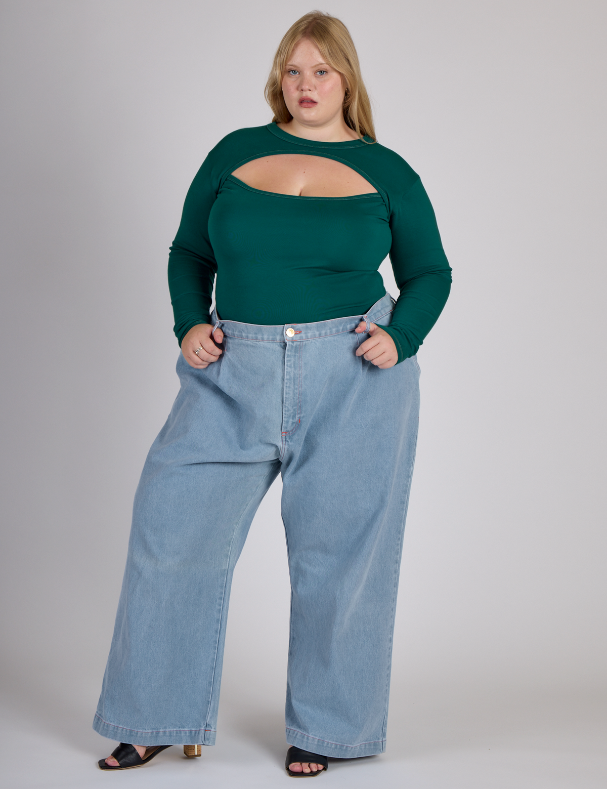 Juliet wearing the Hunter Green Long Sleeve Porthole Tee tucked into Light Wash Denim Wide Leg Trousers