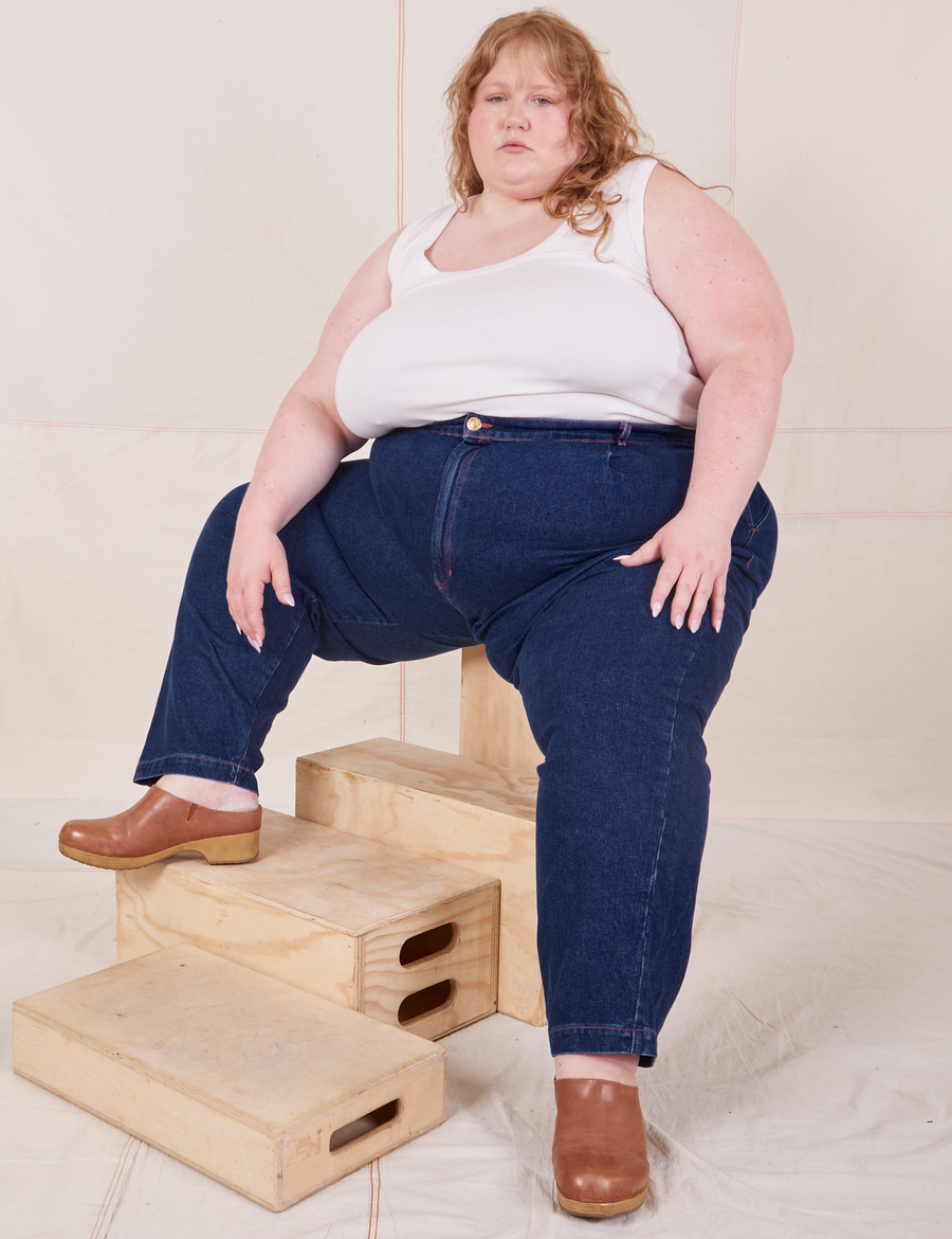 Catie is sitting on a wooden crate wearing  Denim Trouser Jeans in Dark Wash and vintage off-white Cropped Tank Top