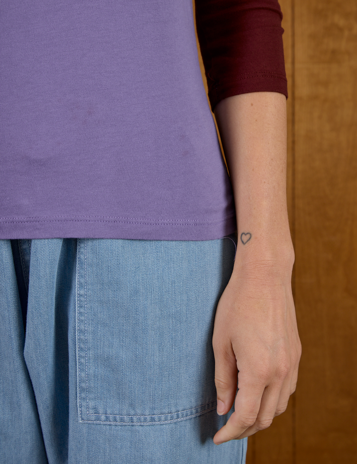 Close up of the hem on the Faded Grape/Wine Colorblock Raglan Tee worn by Alex