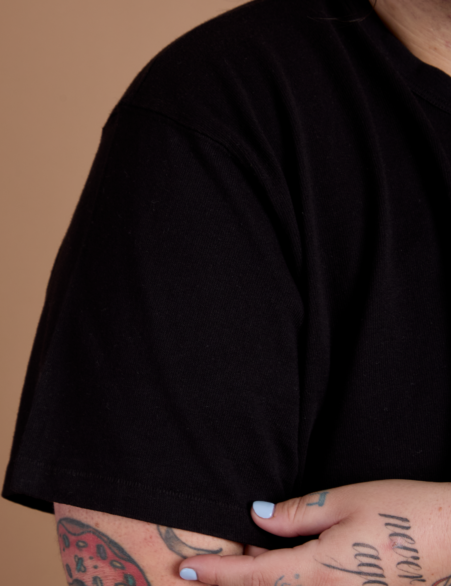 Close up of Burly Tee in Basic Black sleeve on Sam