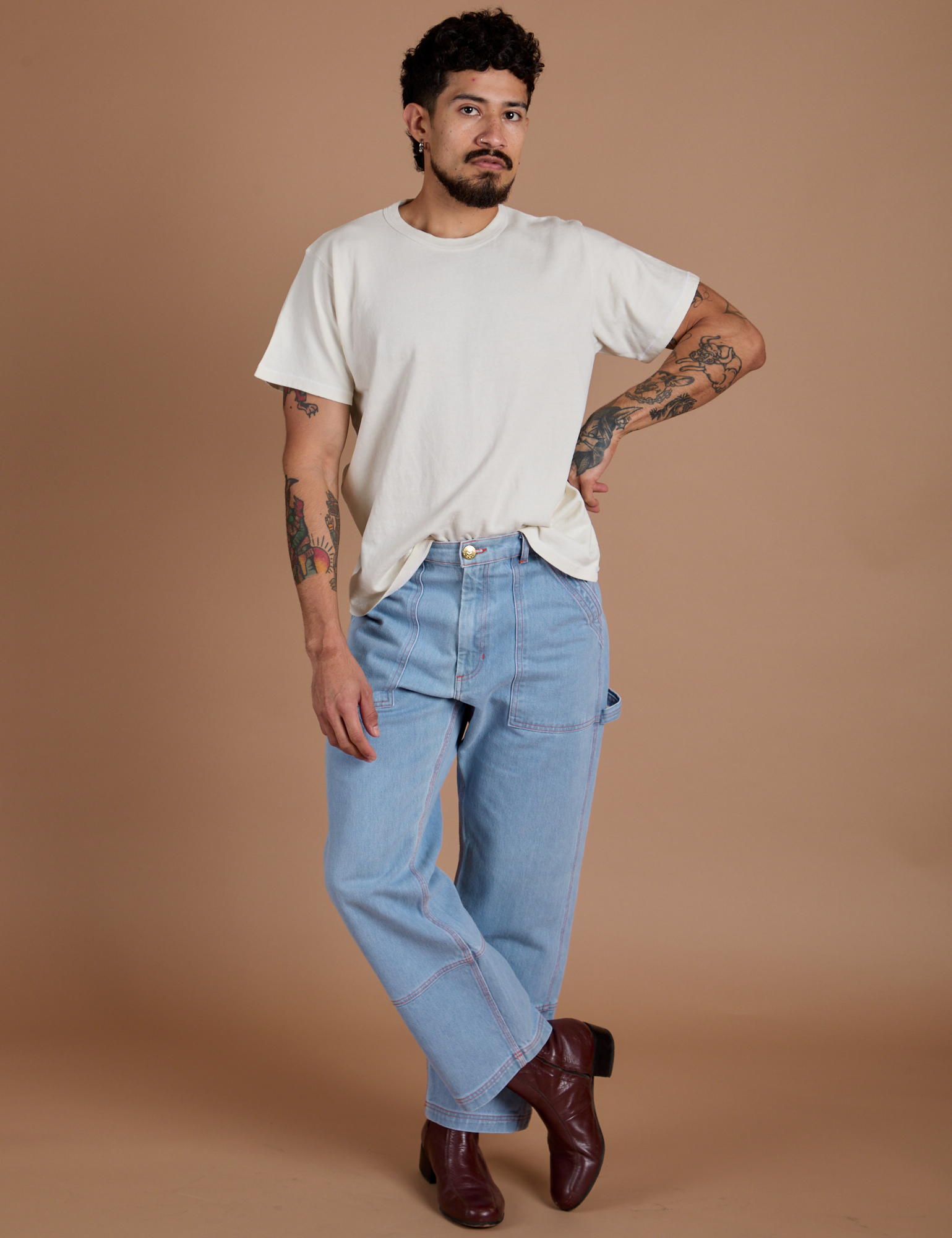 Jesse is 5'8" and wearing S Burly Tee in Vintage Tee White paired with light wash Carpenter Jeans