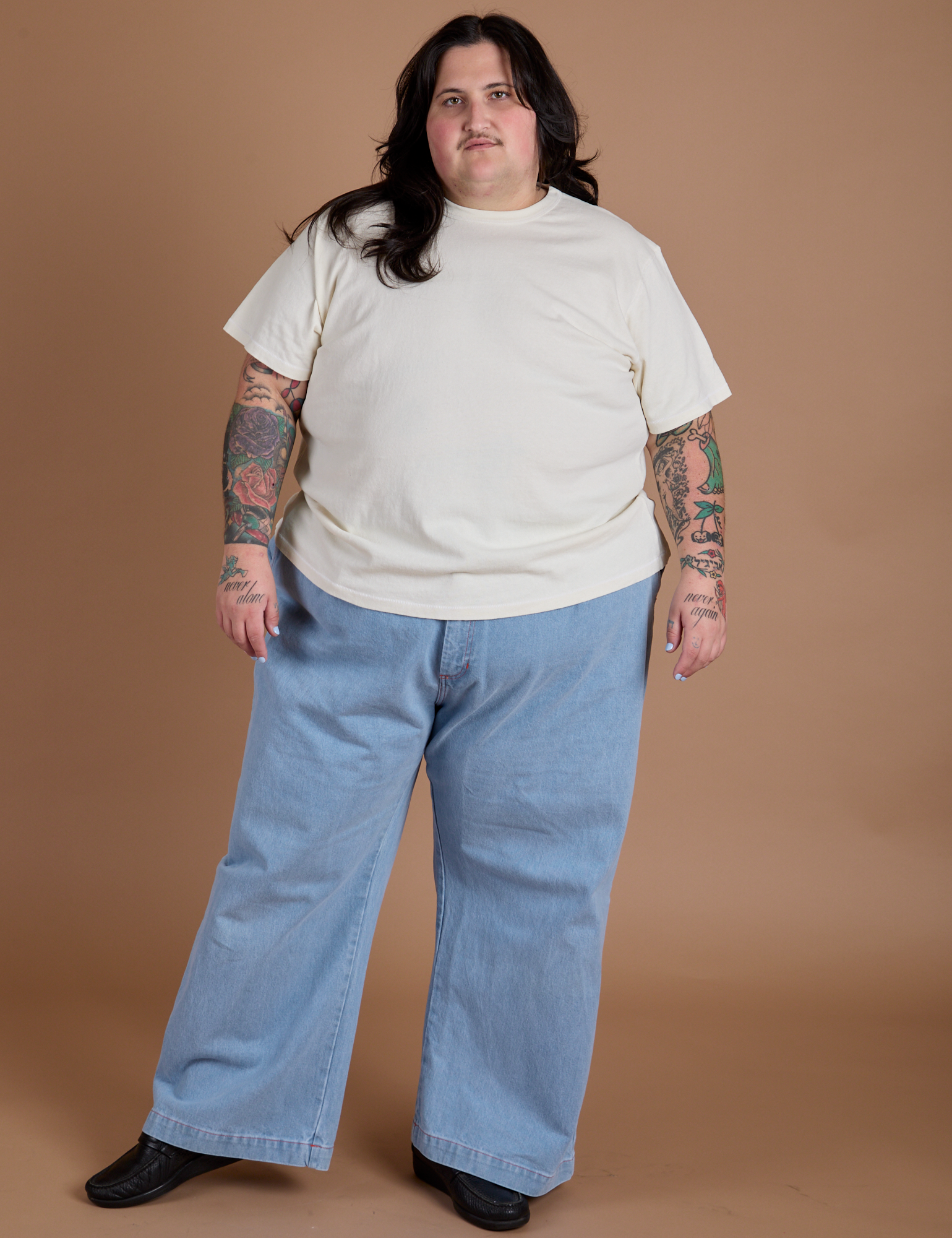 Sam is wearing Burly Tee in Vintage Tee White and light wash Indigo Wide Leg Trousers