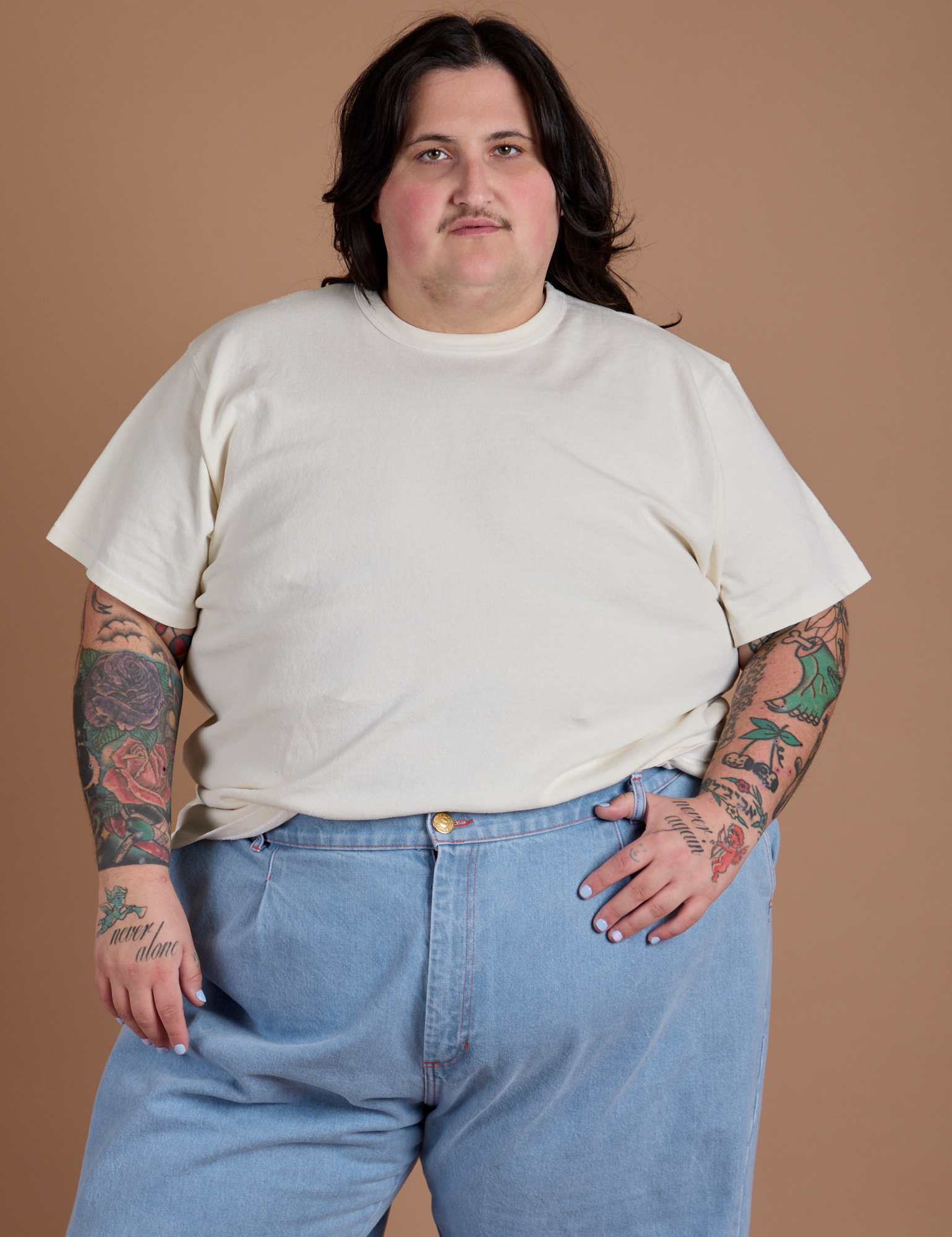 Sam is wearing Burly Tee in Vintage Tee White tucked into light wash Indigo Wide Leg Trousers