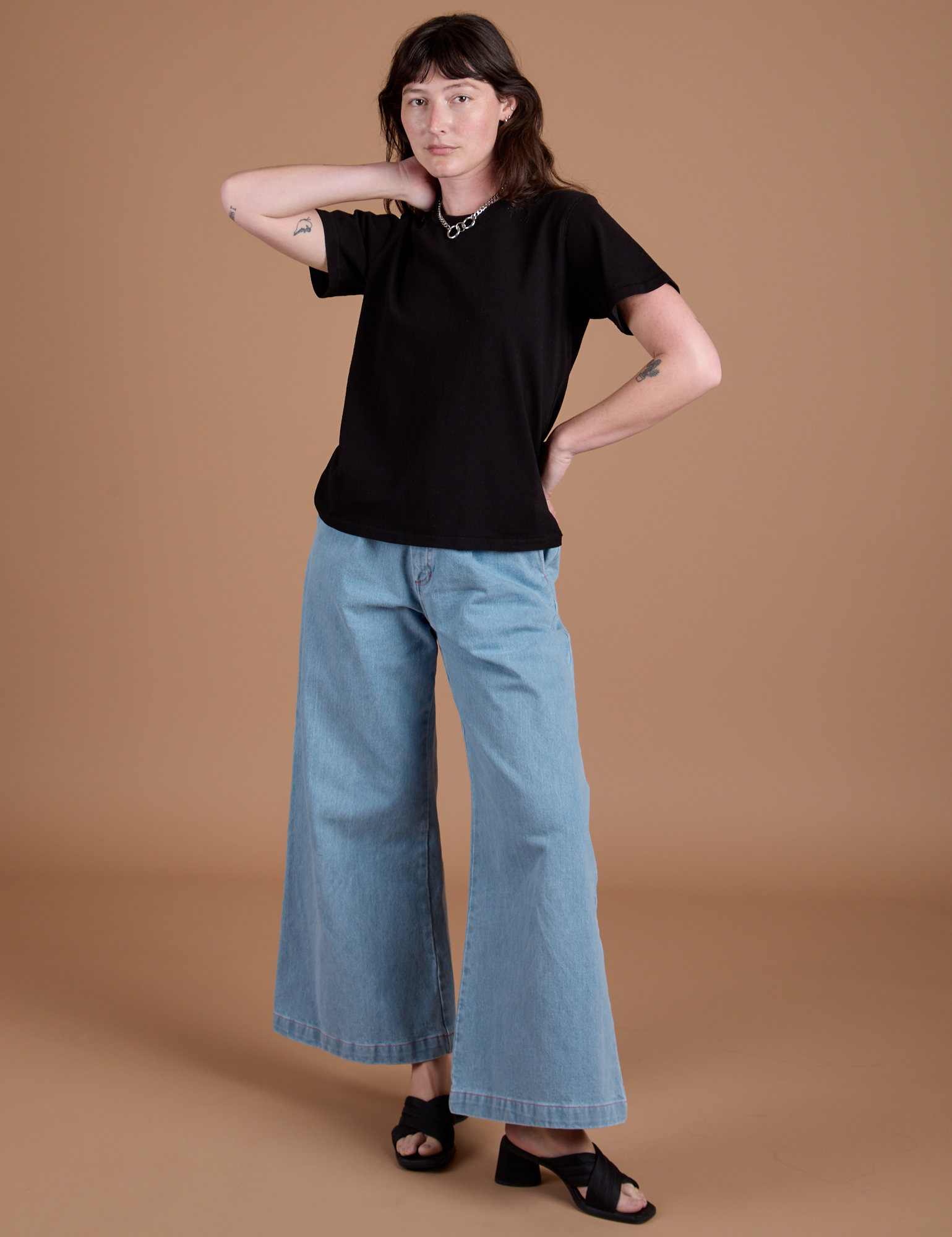 Alex is 5'8" and wearing P Burly Tee in Basic Black paired with light wash Indigo Wide Leg Trousers