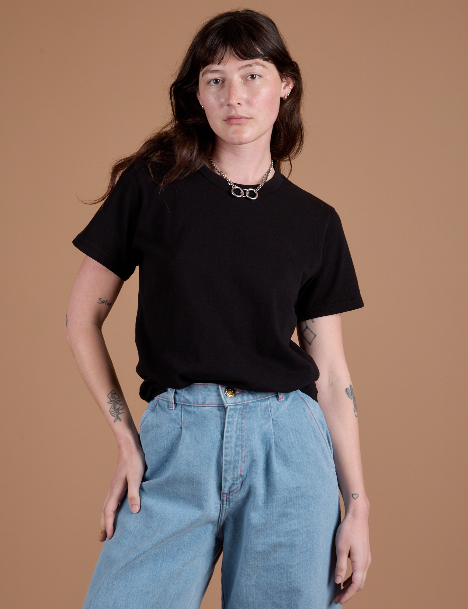 Alex is wearing Burly Tee in Basic Black tucked into light wash Indigo Wide Leg Trousers
