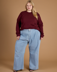 Juliet wearing the Red Wine Long Sleeve Burly Tee tucked into the Light Wash Wide Leg Denim Trousers