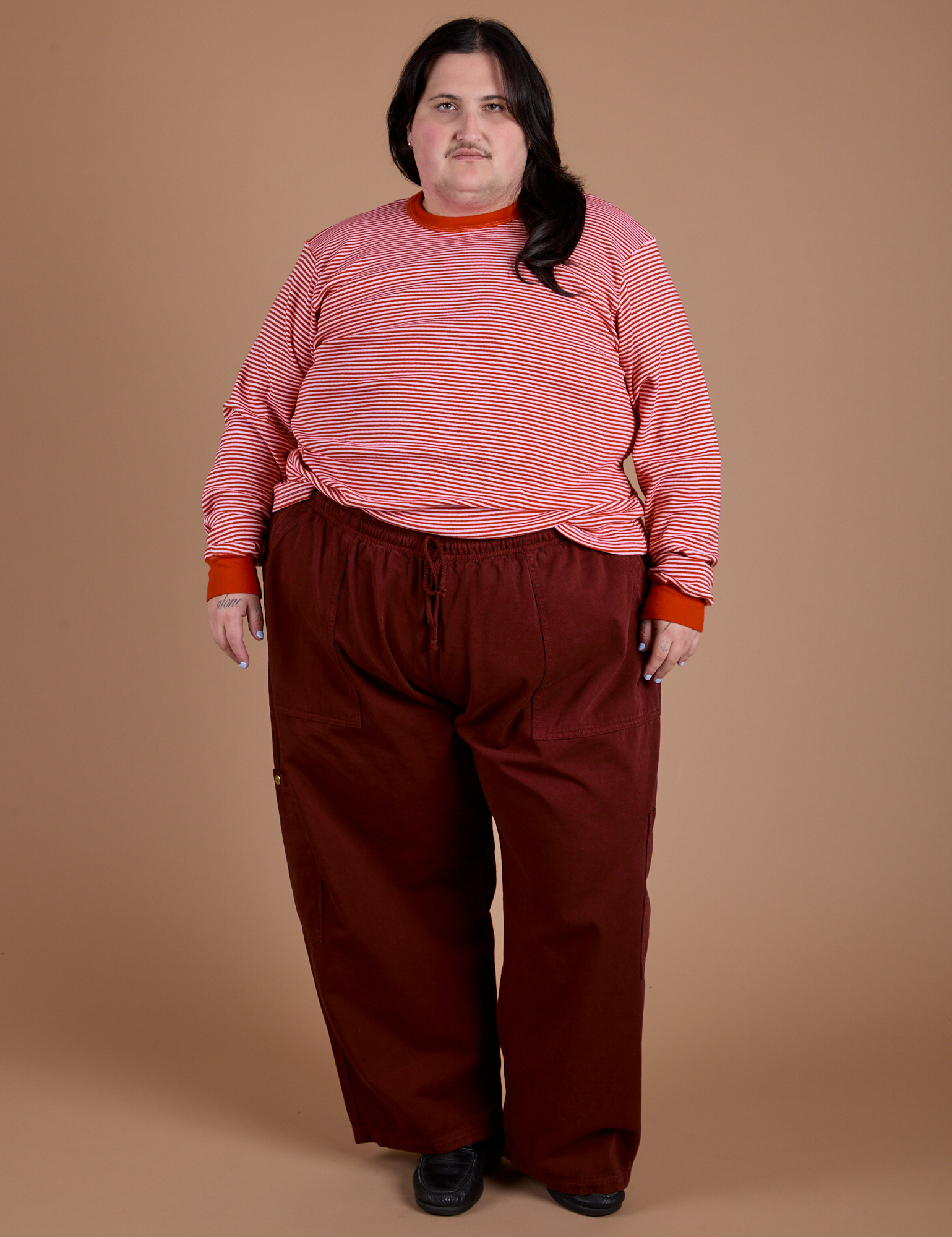 Sam is wearing  Long Sleeve Burly Tee in Red/White Stripe and red wine Drop Pocket Cargo Pants