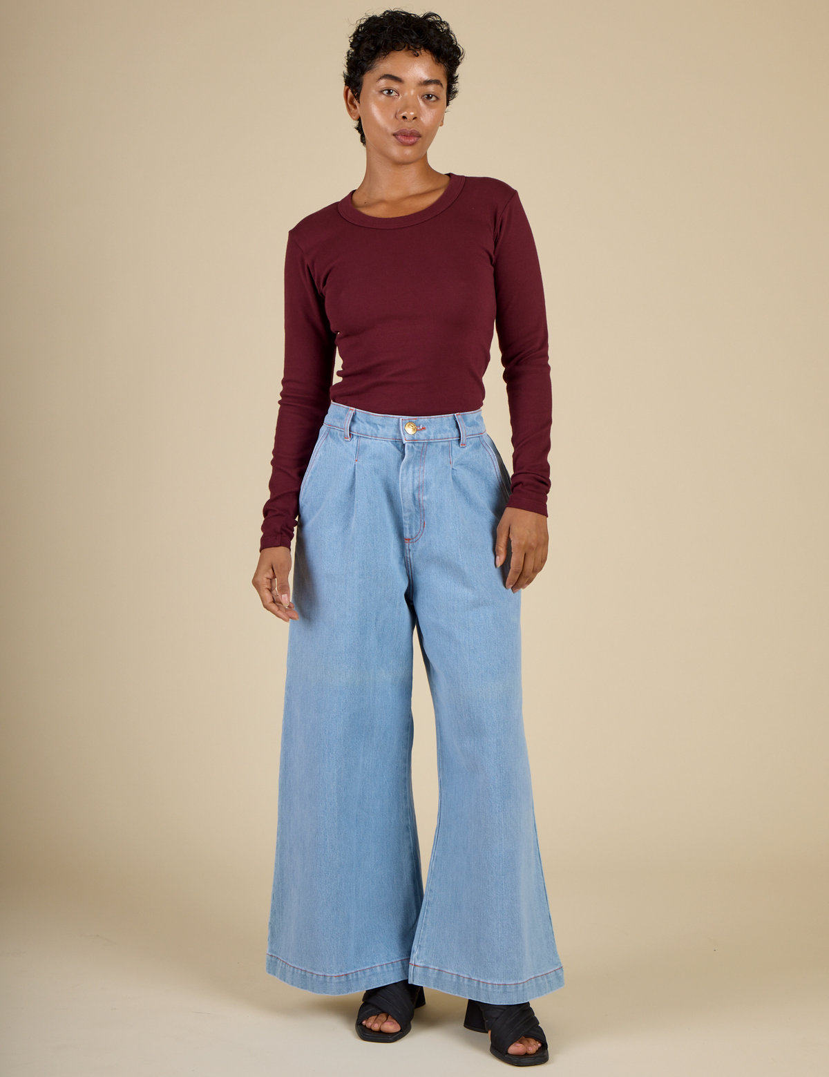 Mika wearing the Red wine Long Sleeve Baby Tee tucked into the Petite Light Wash Wide Leg Denim Trousers