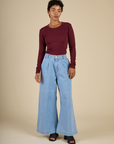 Mika wearing the Red wine Long Sleeve Baby Tee tucked into the Petite Light Wash Wide Leg Denim Trousers