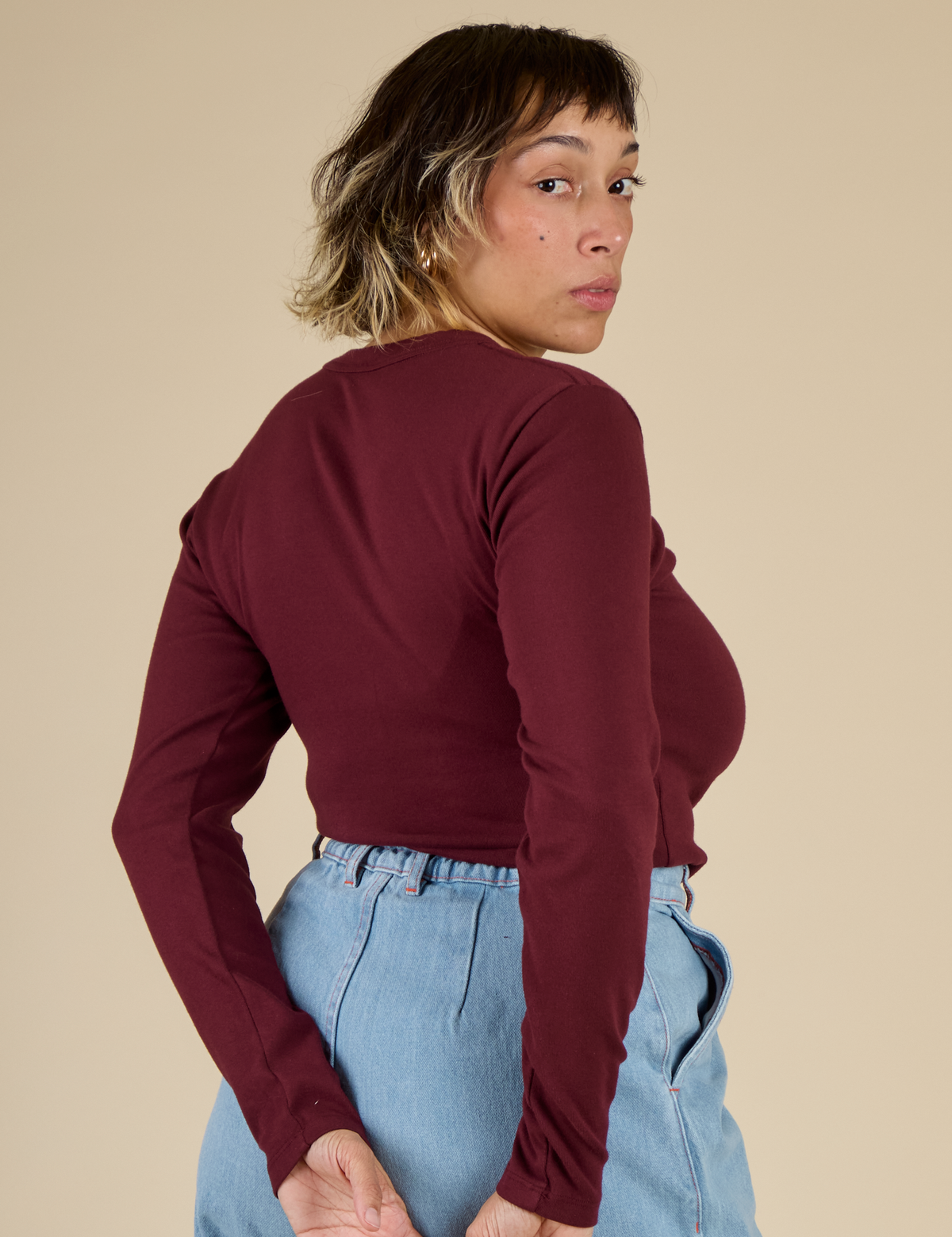 Angled back view of Mika wearing the Red wine Long Sleeve Baby Tee