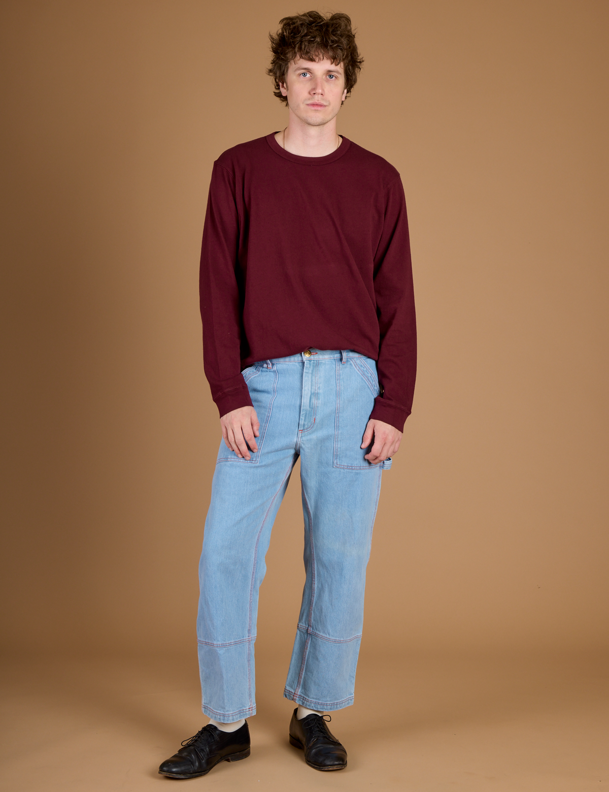 Quinn wearing the Red Wine Long Sleeve Burly Tee tucked into the Light Wash Carpenter Jeans