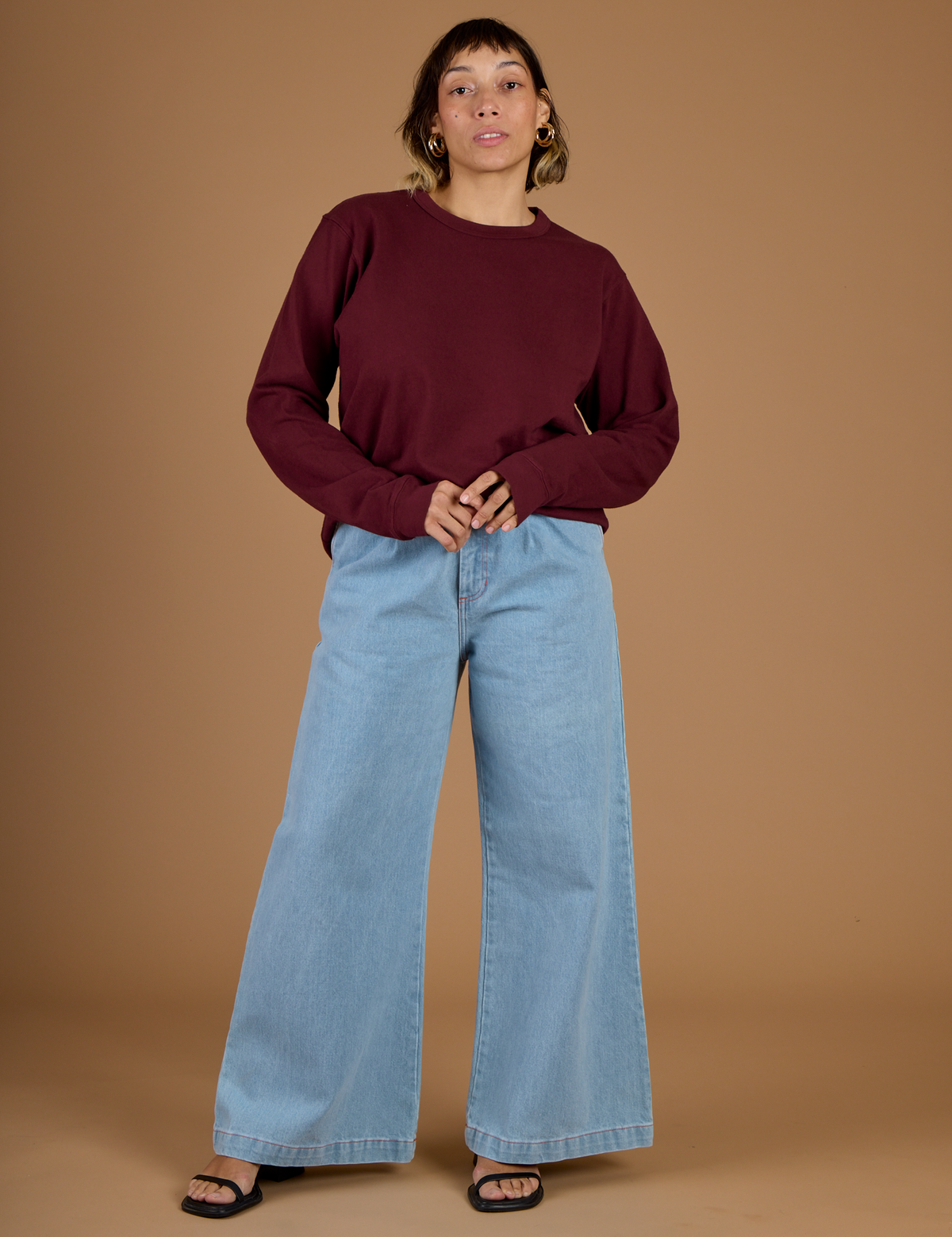 Tiara wearing the Red Wine Long Sleeve Burly Tee tucked into Light Wash Wide Leg Denim Trousers