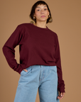Tiara is wearing the Red Wine Long Sleeve Burly Tee tucked into the Light Wash Wide Leg denim Trousers