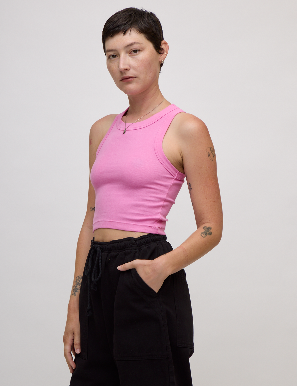 Angled side view of Alex wearing the P Bubblegum Pink Deep Cut Racerback