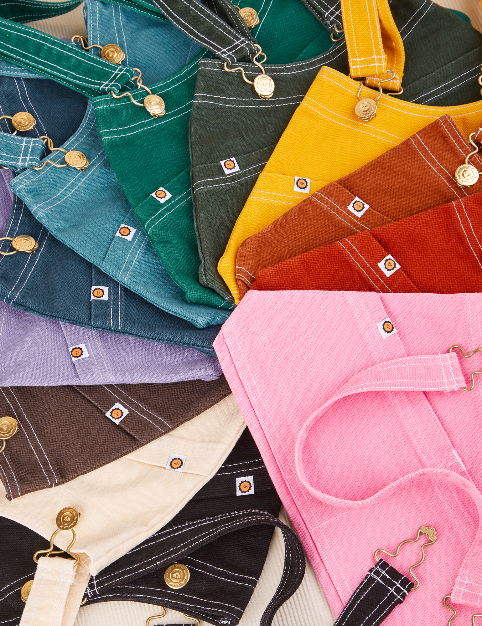 Overall Handbags in an rainbow of colors laid flat in a circular path