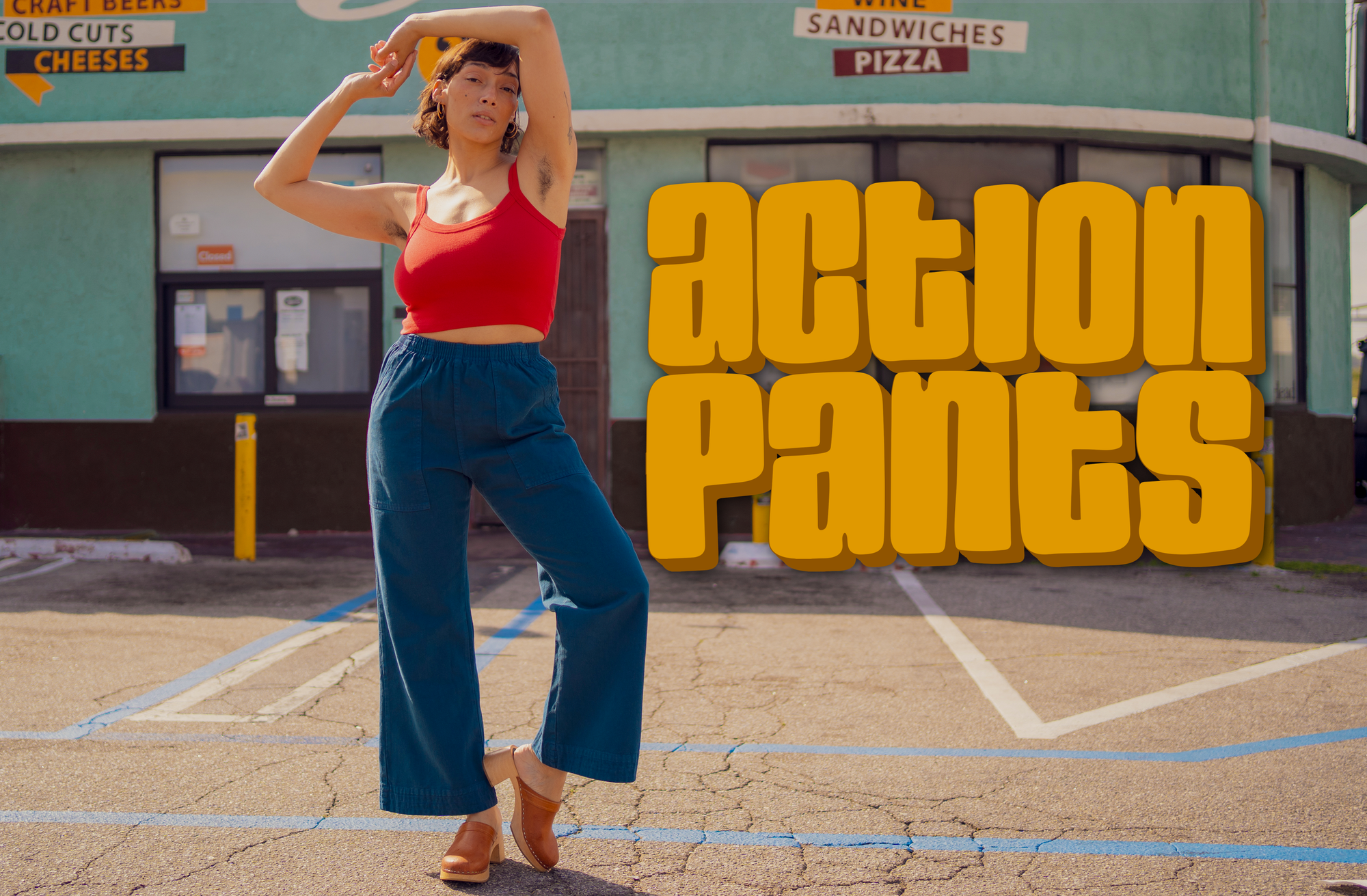 Tiara is wearing a Cropped Cami in Mustang Red and Action Pants in Lagoon